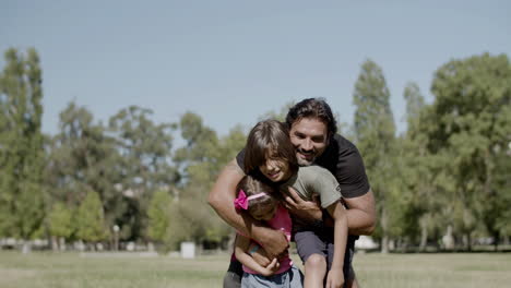 Long-shot-of-dad-with-disability-hugging-children-in-park